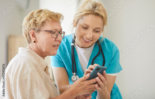 Wallpaper Mural Nurse teaching senior woman using mobile phone, girl explaining smartphone health data and digital tools to elderly patient during consultation in clinic. Caregiver training elderly patient Torontodigital.ca