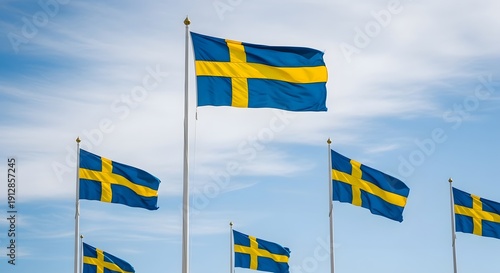 Multiple swedish flags waving in the wind against a cloudy sky