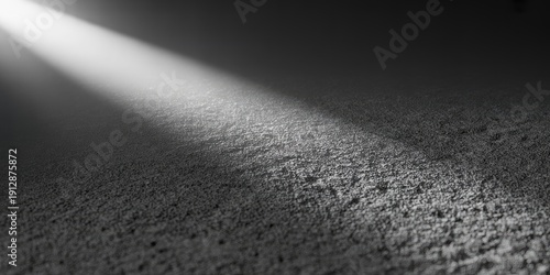 A dramatic black and white photo of a beam of light on a textured surface