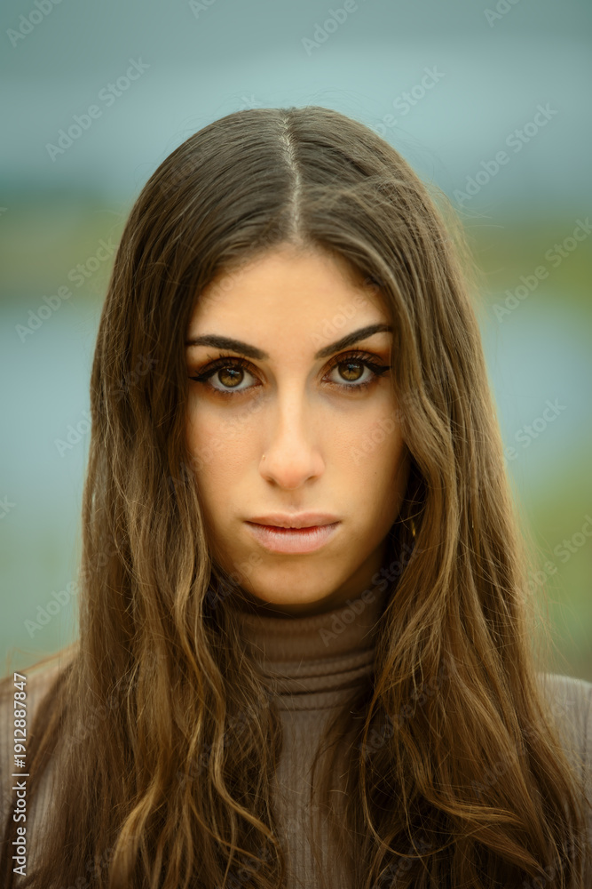 Naklejka premium Intense female portrait with a direct gaze and a blurred natural background