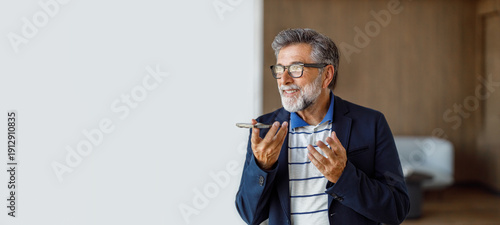 Quadro em tela Confident mature businessman in eyeglasses using mobile phone to send voice mess