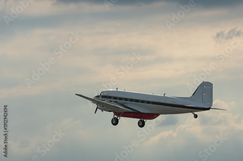 Military plane flying through the sky and clouds on nature background