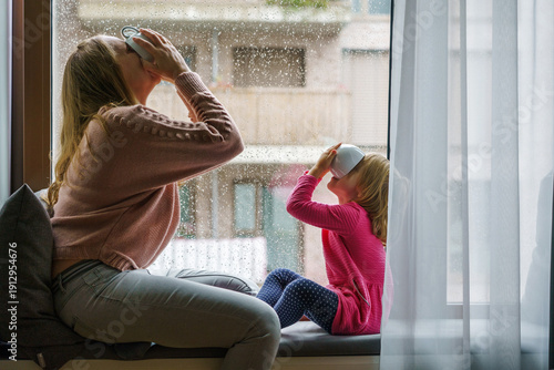 mother and daughter relaxing, drinks tea by window on rainy day, Cozy, Home, Lifestyle, Indoor, Relaxation, Comfort 