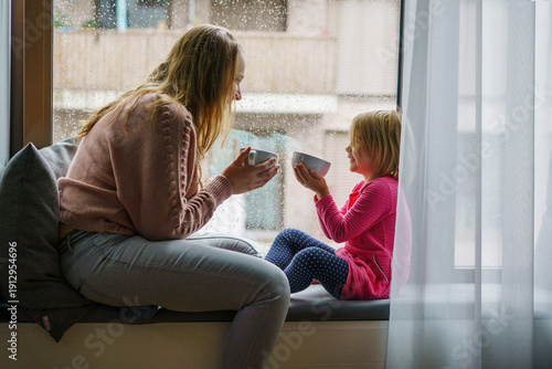 mother and daughter relaxing, drinks tea by window on rainy day, Cozy, Home, Lifestyle, Indoor, Relaxation, Comfort