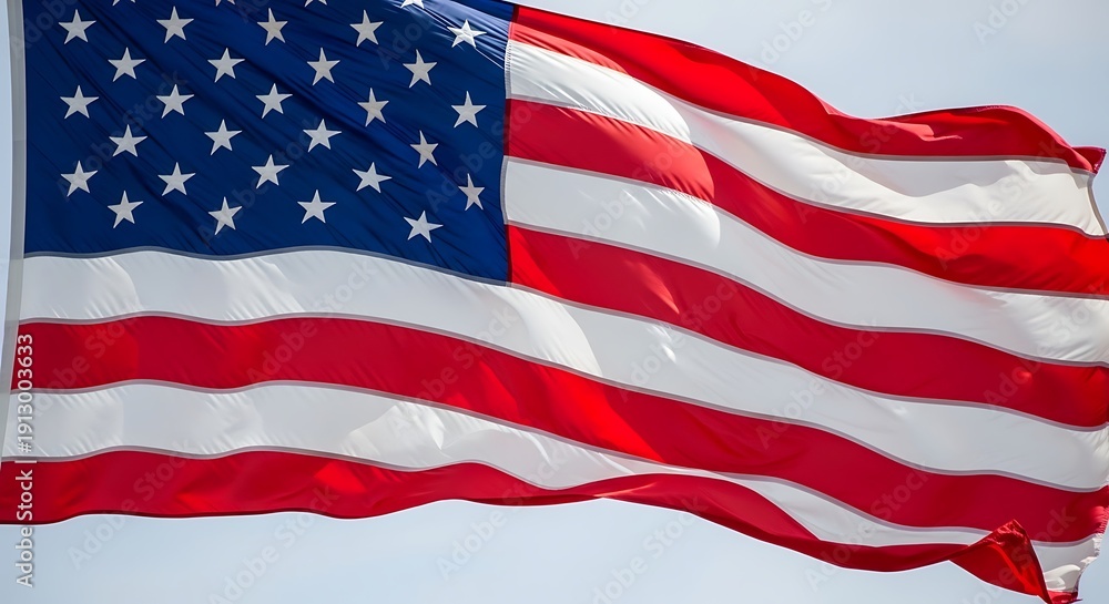 Obraz premium The American flag waving proudly in the wind against a clear sky