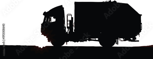 Large refuse truck silhouette drives along a textured, dark road surface under a brilliant white sky.