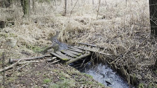 Wallpaper Mural Damaged wooden footbridge over small creek after winter season, documenting infrastructure decay and impact of weather on rural landscape
 Torontodigital.ca