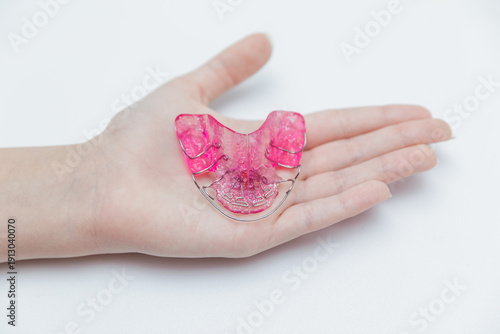 Photos Pink removable orthodontic plate for teeth alignment on child's open palm, pedia