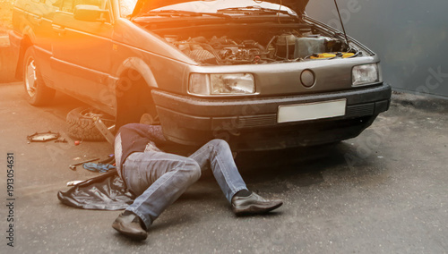 Obraz na plátně Car repair in a garage with a mechanic working under the hood in urban setting d