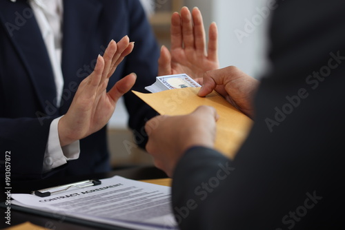 Businesswoman firmly rejecting bribe money offered by businessman in exchange for a contract, the ongoing battle against corruption and the importance of ethical integrity in business.