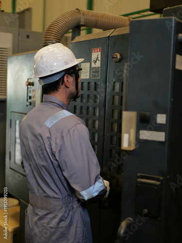 Industrial engineer operating CNC machine in automotive manufacturing factory