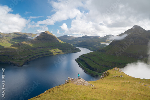 Panoramic view of Faroe Islands fjord with hiker from above