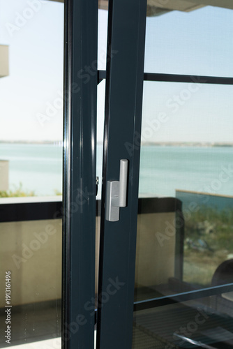 PVC Terrace Door. A close-up of a metal or PVC balcony door, slightly open. Selective focus, shallow depth of field.