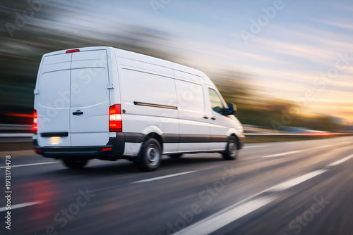 White delivery van moving at a fast speed seen from the rear with tail lights on. Motion blur image with copy space.
