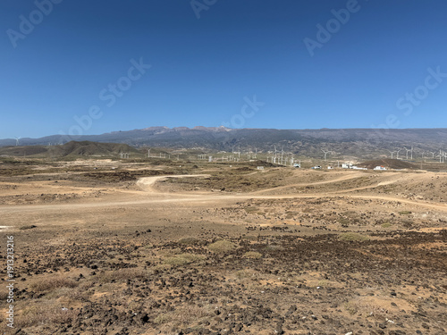 Costa árida de Tenerife con aerogeneradores y el Teide al fondo