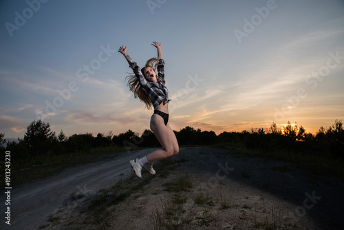 Wallpaper Mural Happy Young Woman Jumping on Rural Road at Sunset Torontodigital.ca