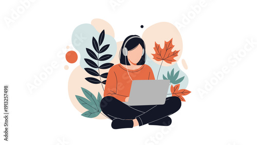 Young woman wearing headphones works on a laptop while sitting cross-legged among colorful autumn leaves in fall.