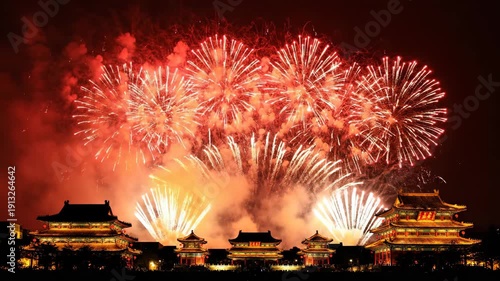 Spectacular red and gold fireworks explode dramatically above the silhouetted traditional chinese palace architecture in this festive night photography shot.