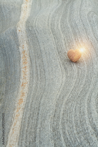 Photos Heart‑Shaped Stone with Light Flare on Textured gneiss ‑Like Rock Surface