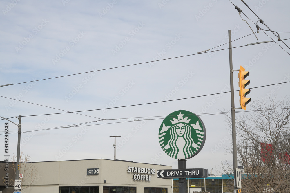 Fototapeta premium wide distant view of round road side mermaid logo sign of Starbucks Coffee Company located here at 23 Leslie St, Toronto