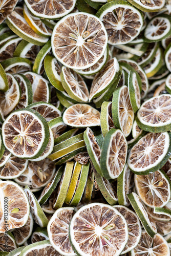 Top view of dried lemon slices arranged in a natural pattern. Detailed food texture background featuring dehydrated citrus fruit, organic ingredients, and healthy culinary elements.