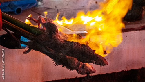 Wet Asian markets.Food tastes disgusting to European.But it's poor country, eat everything here.Providing population with normal food global problem.Process of roasting of wood rat.Put it on skewer.ID