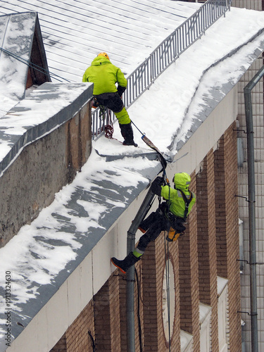 Employees of the municipal service remove snow from the roof of the building, after a heavy snowfall. 