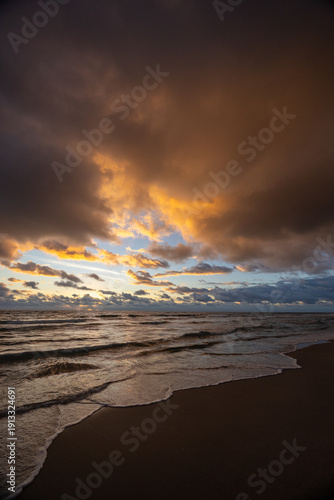 Dramatic Sunrise Over Ocean Beach with Golden Clouds and Rolling Waves Vertical