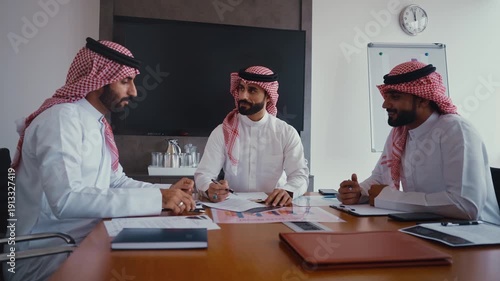 Arab businessmen wearing emirati kandura meeting in office for business deal - Corporate business group of middle-eastern people working in an international company in middle east 