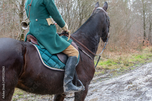 Tableau sur toile Rider in traditional green hunting coat on horse in muddy forest track