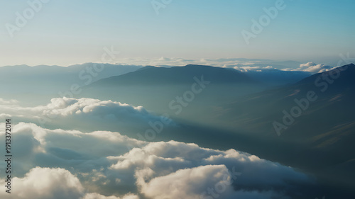 Aerial view of mountains covered with thick white clouds and blue sky