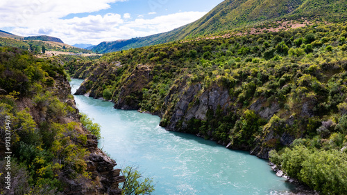 Bild auf Leinwand blue river surrounded by green trees mountains hills kawarau river queenstowm ne