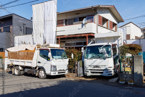 住宅街の解体工事現場と廃材を運搬するトラック