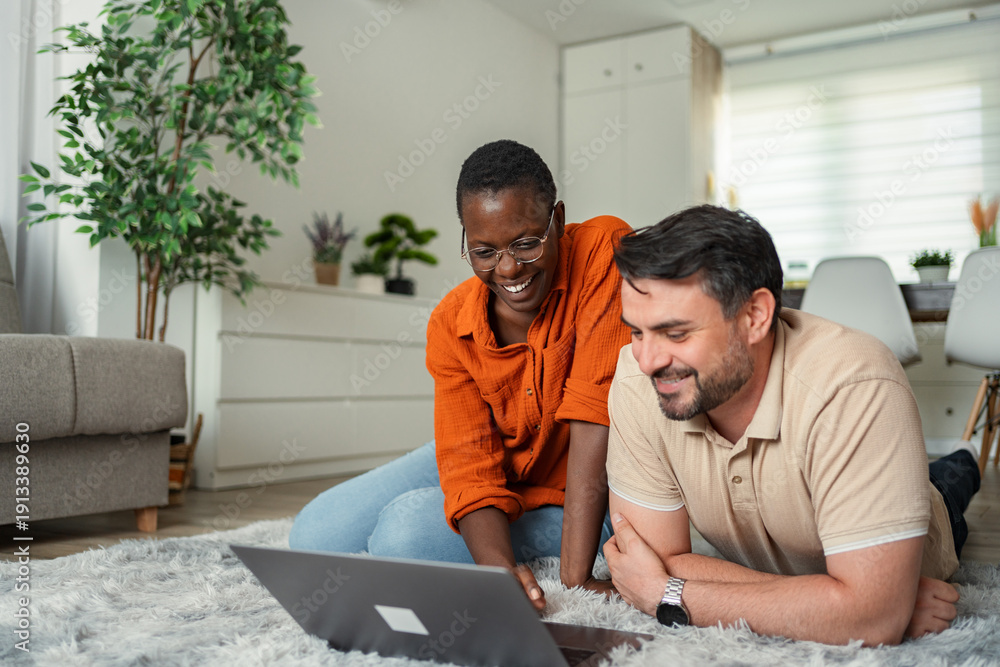Obraz premium Happy couple smiling and using laptop at home
