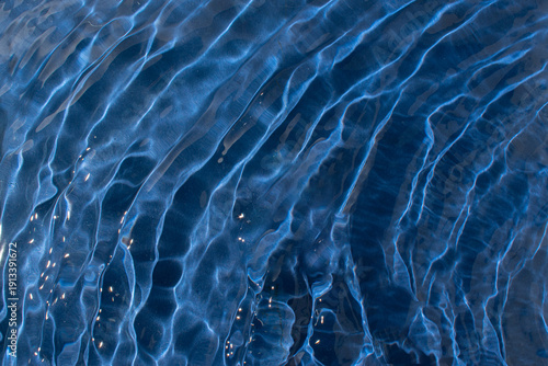 Water with a shining rippled texture on a dark blue background. Abstract Water surface background idea. Abstract summer water background.
