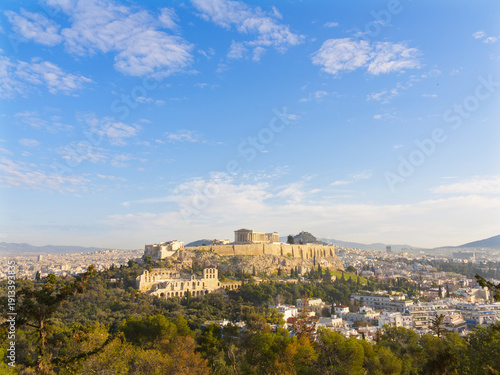 Ancient Acropolis citadel overlooking Athens cityscape under blue sky with scattered clouds