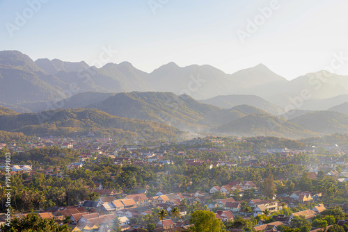 Scenery view small town of Luang Prabang city center surround big mountains and river, Cityscape in the evening with golden sunlight during the sunset, The ancient capital province in northern Laos.