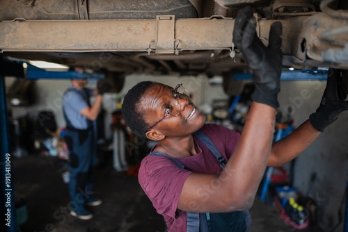 Wallpaper Mural Young african female mechanic repairing car in a workshop Torontodigital.ca