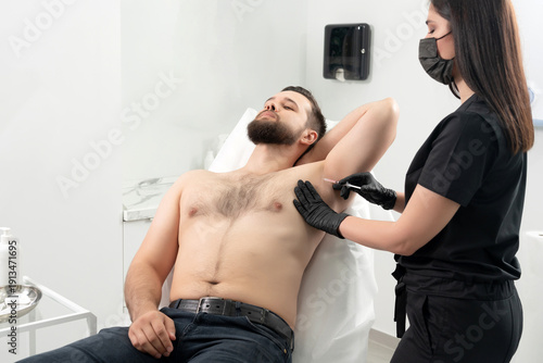 Doctor doing injection from hyperhidrosis. Man receiving an underarm treatment in cosmetology clinic