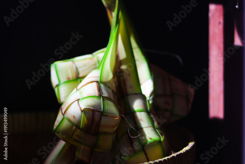 Ketupat or rice dumpling is traditional Muslim food during the celebration of Eid al-Fitr. Ketupat  in bamboo bracket with low light.