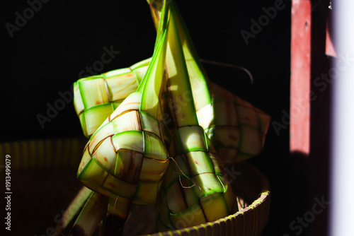 Ketupat or rice dumpling is traditional Muslim food during the celebration of Eid al-Fitr. Ketupat  in bamboo bracket with low light.