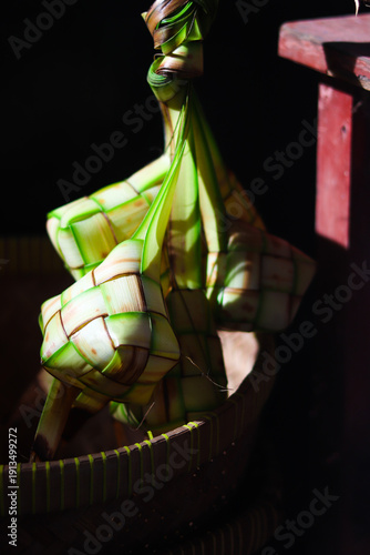 Ketupat or rice dumpling is traditional Muslim food during the celebration of Eid al-Fitr. Ketupat  in bamboo bracket with low light.