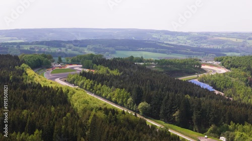 belgium f1 formula one circuit sweeps through ardennes forest eau rouge section carving bends asphalt bordered by safety barriers grandstands countryside hills spa francorchamps 