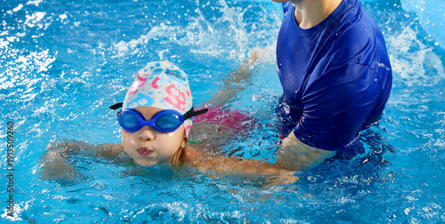 Cuadro en lienzo Trainer teaching little boy how to swim in indoor pool with pool floating board