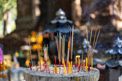 Incense and fire candles with ashes and smoke in Incense burner from Buddhists for make a wish or pray to buddha statue or sacred deities by belief in Buddhism for lucky in Asia at Thailand temple