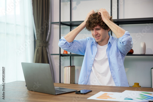 young man working on laptop computer and having a headache at home