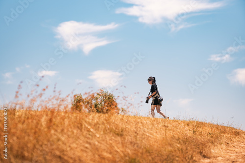 Foto Low angle view of woman walking in the field on hilltop under the blue sky, Moun
