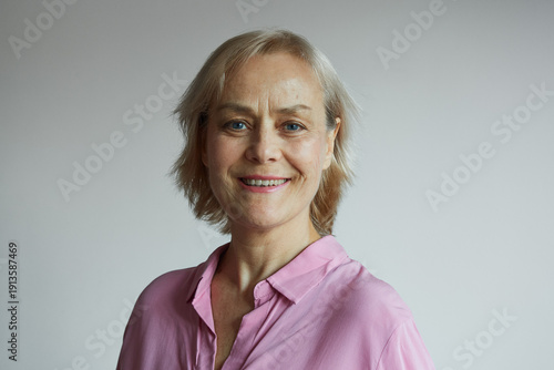 Beautiful smiling mature woman 60 years old on gray background, natural aging, natural beauty