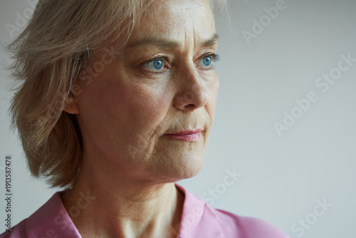 Close-up of a mature woman's face in her 60s on a gray background, natural aging, natural beauty