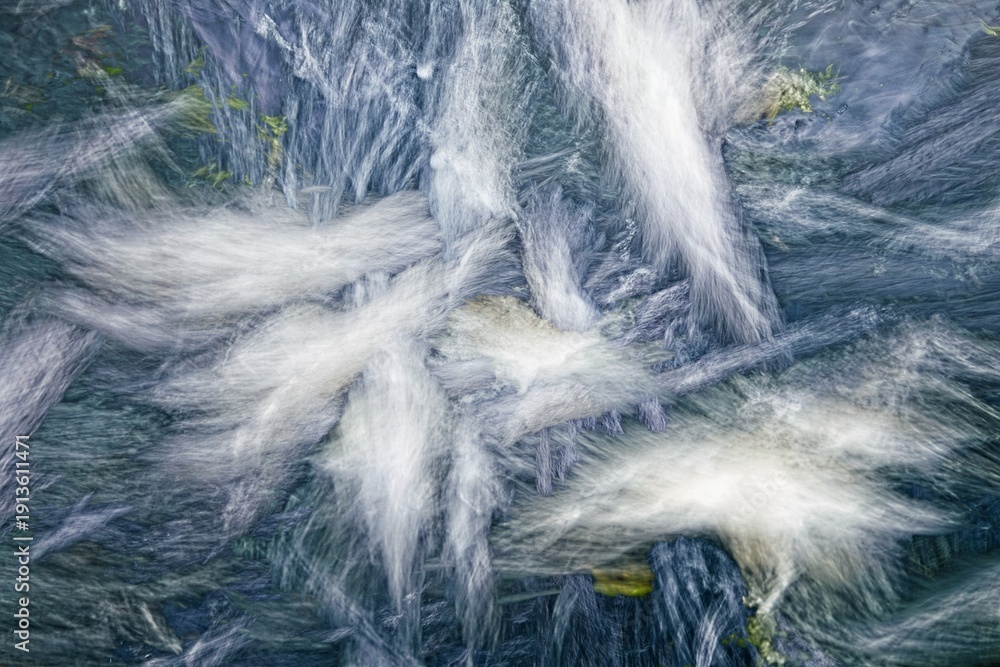 Fototapeta premium Whispers of the Stream: The mesmerizing blur of a stream's dance, as water cascades over rocks, evoking a sense of tranquil movement, serenity and timelessness.